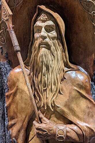 A statue of the Norse god Odin, long of beard and wearing a hood, with a spear in his hand and a cloak over his shoulders, from the Epcott Center's Norway exhib